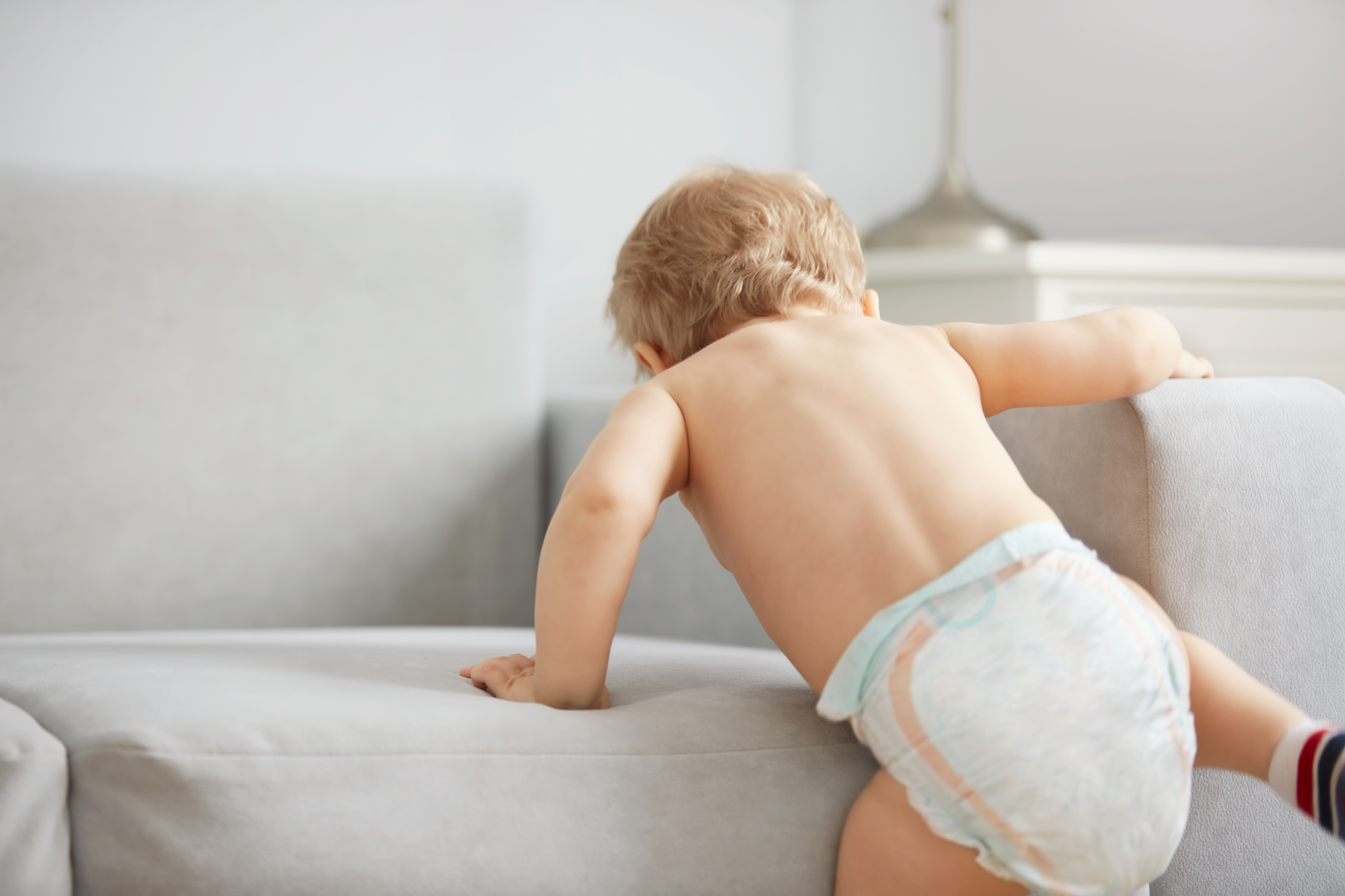 The first independent steps of the kid in the bedroom at the weekend. Casual lifestyle photo series in real life interior